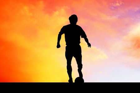 Silhouettes of footballers on the sunset skyの写真素材