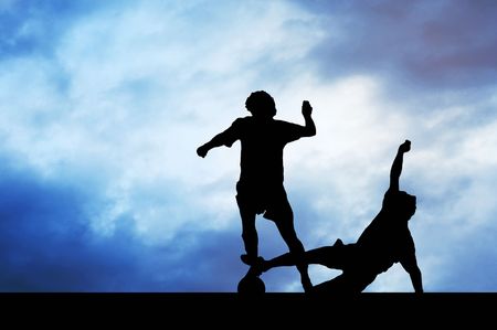 Silhouettes of footballers on the sunset skyの写真素材