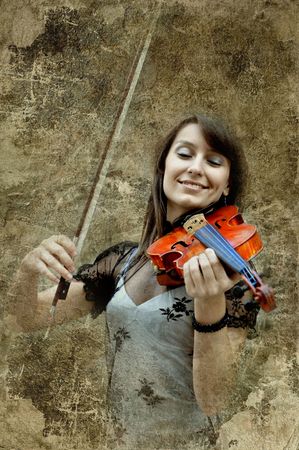 Beautiful female violinist playing violin on the grunge backgroundの写真素材