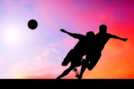 Silhouettes of footballers on the sunset skyの写真素材