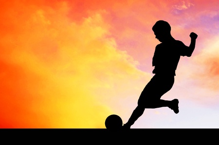 Silhouettes of footballers on the sunset skyの写真素材