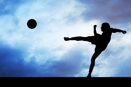 Silhouettes of footballers on the sunset skyの写真素材