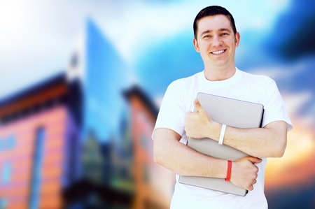 Young happy man or student with laptop and phone on the business background