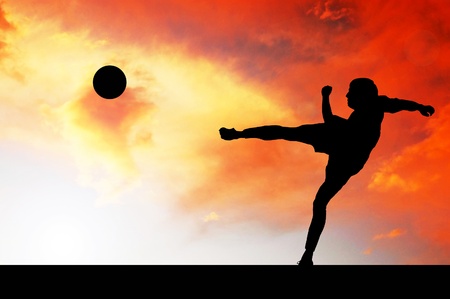 Silhouettes of footballers on the sunset skyの写真素材