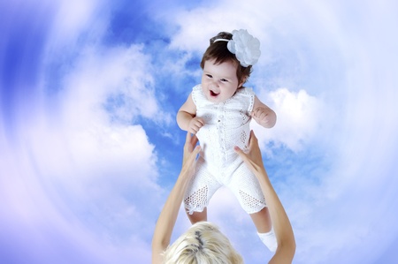 Child in white in mother hands under sky backgroundの写真素材