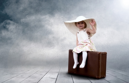 Little girl sitting outdoors on the vintage baggageの写真素材