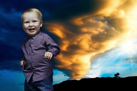 Smiling child stay under dramatic sky with cloudsの写真素材