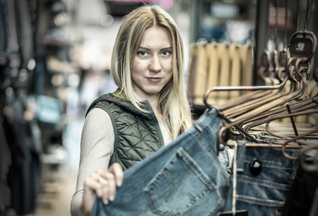 Beautiful blonde female looking jeans in the boutiqueの写真素材