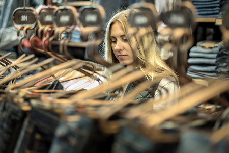 Beautiful blonde female looking jeans in the boutiqueの写真素材