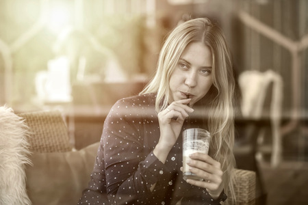 Beautiful blonde female drink coffee in cafeの写真素材