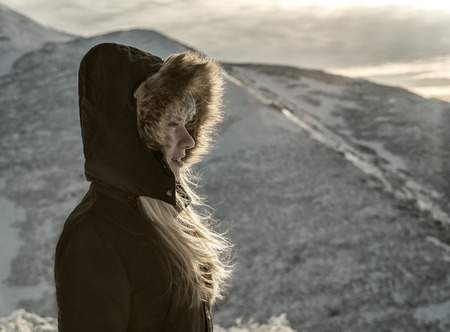 Woman stay under sun light. Beautiful winter mountains view.の写真素材