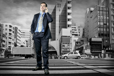 Businessman speaking by phone on the crossroadの写真素材