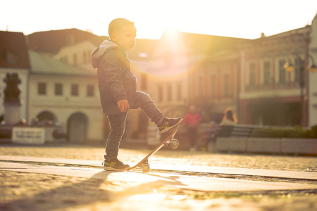Child with skateboard on the street at sunset light.の写真素材