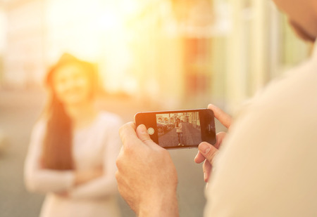 Touristic couple shooting on the modile phone at the city streets under sunlight.の写真素材