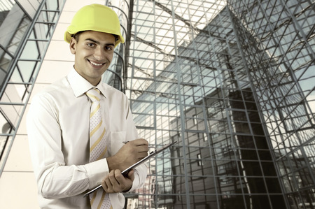 Young architect wearing a protective helmet standing on the building outdoor background
