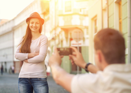 Touristic couple shooting on the modile phone at the city streets under sunlight.の写真素材
