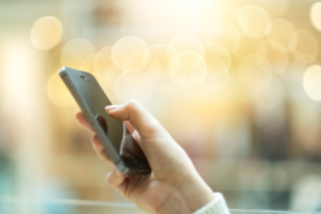 Womens hand using mobile phone on the bokeh background