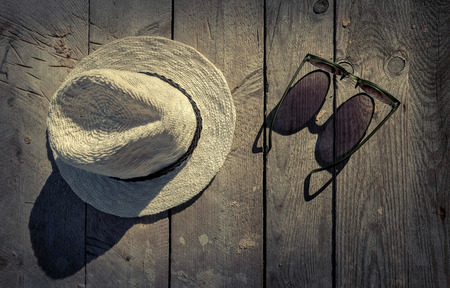 Sunglasses and hat on the wooden texture in sunday.の写真素材