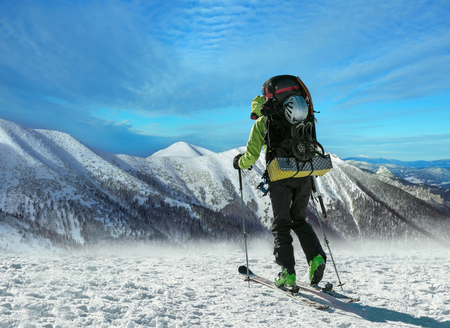 Men with backpack at ski goes to the top of mountain in sun dayの写真素材