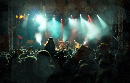 Rock concert, silhouettes of happy people raising up handsの写真素材