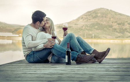 Romantic Couple sitting on the pier with red wine.の写真素材