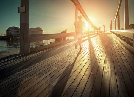 Woman running on the bridge under sunlight.の写真素材