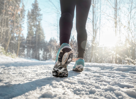 Woman Running at snowly winter under sunlight.の写真素材