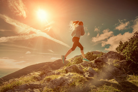 Female running in mountains under sunlight.の写真素材