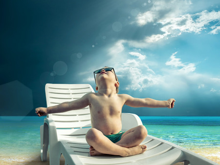 Child in sunglasses fun near the water under sunlightの写真素材