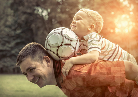 Father and son playing football in park at sunny dayの写真素材