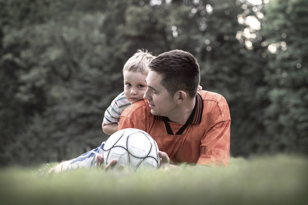 Father and son playing football in park at sunny dayの写真素材