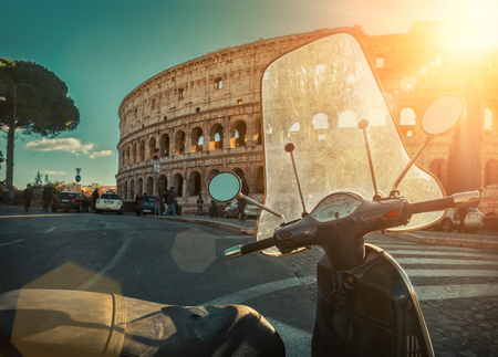Retro scooter stay near the Roman Coliseum under blue sky with sun light at day time. Scooters and Coliseum are the symbols of Rome - most popular historical travel place of the Italy and in the world.のeditorial素材