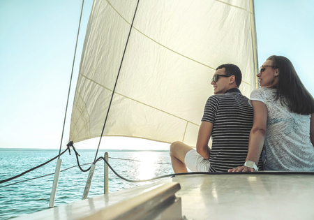 Romantic couple in love on sail boat at sunset under sunlight on yacht - Happy exclusive alternative lifestyle concept - Love story of two caucasian young people.の写真素材