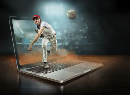 Caucassian baseball Players in dynamic action with ball in a professional sport game play on the laptop in baseball under stadium lights.の写真素材