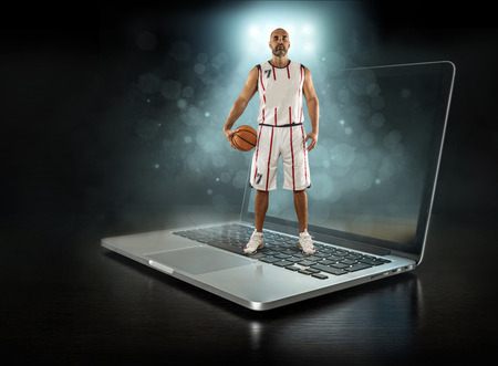 Caucassian Basketball Player in dynamic action with ball in a professional sport game play on the laptop.の写真素材
