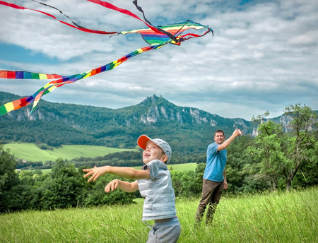 Happiness father and son launch a kite to blue sky on the field in summer sunny day.の写真素材