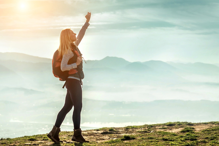 Happy woman tourist stay on the green grass on the peak of mountain and look on the nice fog view. Concept freedom.の写真素材