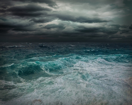 Stormy sea view  near coastline at evening time. Waves, splashed drops under dark dramatic sky.