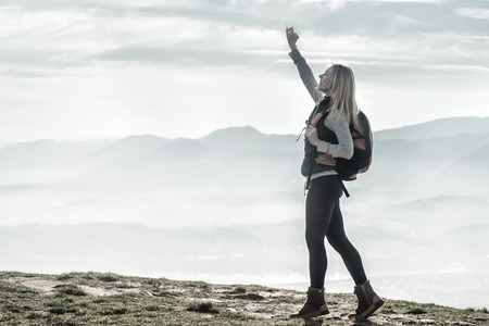 Happy woman tourist stay on the green grass on the peak of mountain and look on the nice fog view. Concept freedom.の写真素材