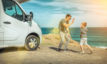 Happiness father and son, stay near them white travel car and look on the beautifull ocean coastline view in sunny day. Freedom, Family, Travell, Journej, Togetherness concept.の写真素材