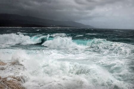 Stormy sea view  near coastline at evening time. Waves, splashed drops under dark dramatic sky.の写真素材