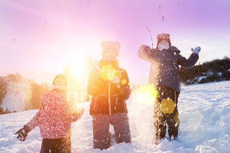 Children playing snowballs, having fun in the snow, happy winter holidays.