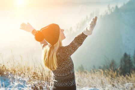 Happy female traveler resting on top of mountain under blue sky with sunlight on sunny winter day, travel vacation, mountain landscape background.の写真素材