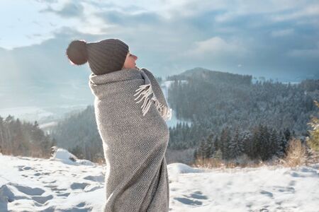 Happy woman traveler stay in snowy mountains and looking on nice winter weather, sunny day.の写真素材