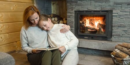 Happy Christmas family, Loving parents mother and child girl sitting near fireplace and fun celebrating festive holiday enjoying feast at homeの写真素材