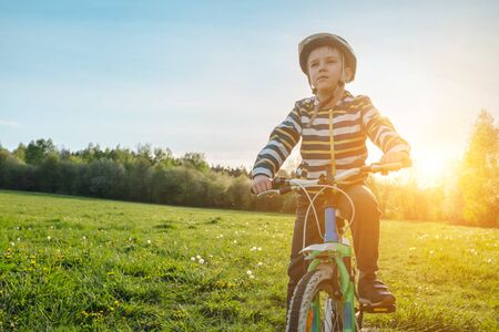 Child on bike in park. Boy going wearing safe bicycle helmets. Little Kid biking on sunny summer day. Active healthy outdoor sport Fun activity.の写真素材