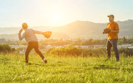 Father and son playing in baseball. Playful Man teaching Boy baseballs exercise outdoors in sunny day at public park. Family sports weekend. Father's day.の写真素材