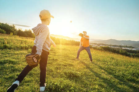 Father and son playing in baseball. Playful Man teaching Boy baseballs exercise outdoors in sunny day at public park. Family sports weekend. Father's day.の写真素材