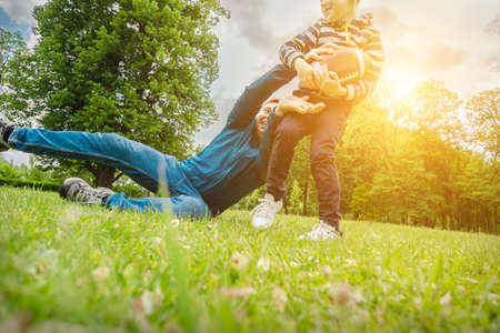 Father and son playing football, Father's day, Playful Man teaching Boy rugby outdoors in sunny day at public park. Family sports weekend.の写真素材