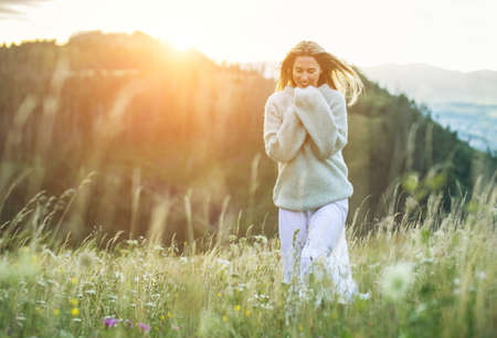 Portrait happy woman enjoying sunset stay on the green grass on the forest peak of mountain. Fresh...